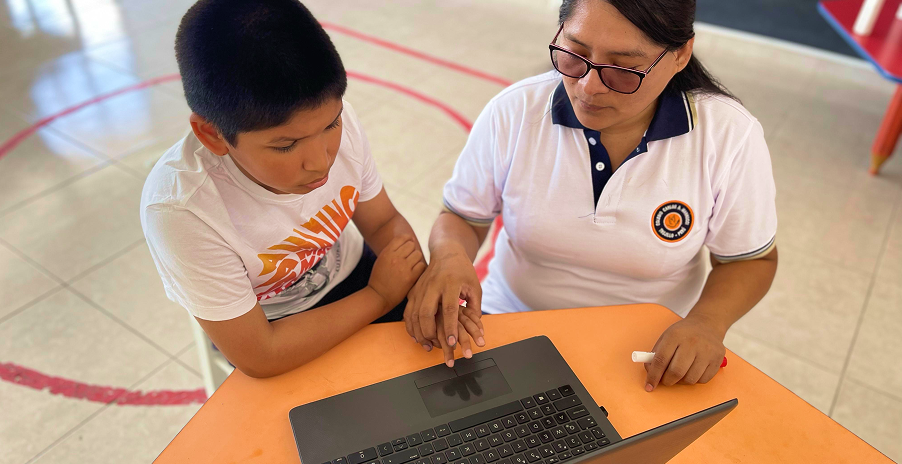 Docente acompañando a un estudiante en primaria